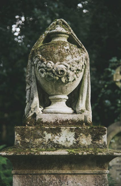A view of an old cemetery with numerous upright headstones and grave markers of varying sizes and shapes, predominantly made of weathered stone with subdued grey and beige tones. Some headstones have 